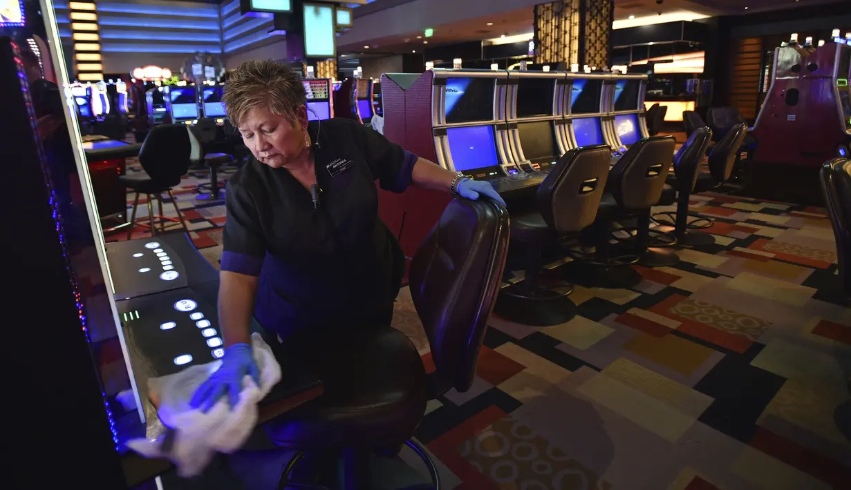 Antonia Garcia membersihkan mesin slot di kasino hotel Planet Hollywood setelah perintah penutupan kasino akibat virus corona COVID-19 di Las Vegas, Amerika Serikat, Rabu (18/3/2020). Para pegawai dirumahkan karena pengunjung menurun sekaligus mencegah penyebaran virus. (AP Photo/David Becker)
