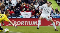 Gareth Bale mencetak gol ketiga Real Madrid ke gawang Getafe yang dikawal kiper Vicente Guaita dalam lanjutan Liga Spanyol, Sabtu malam WIB (16/4/2016). (Liputan6.com/REUTERS/Sergio Perez)