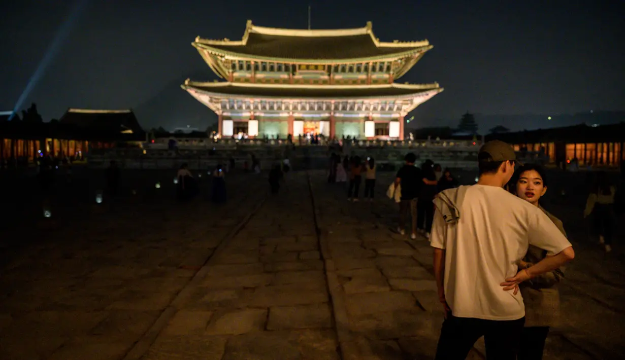 Gambar pada 4 Oktober 2019, wisatawan berdiri di halaman Istana Gyeongbokgung saat kunjungan malam di pusat Seoul, Korea Selatan. Kunjungan malam tersedia pada minggu ketiga dan keempat setiap bulan mulai dari 26 April sampai 31 Oktober, kecuali pada bulan Agustus. (Photo by Ed JONES / AFP)