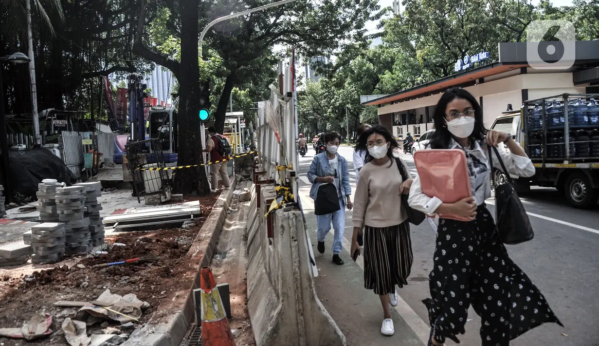 Pejalan kaki melintasi jalur sementara saat proyek revitalisasi trotoar di Jalan Medan Merdeka Selatan, Jakarta Pusat, Selasa (22/11/2022). Pemprov DKI Jakarta mengalokasikan anggaran sebesar Rp 171 miliar dalam Rancangan Anggaran Pendapatan dan Belanja Daerah (RAPBD) DKI Jakarta 2023 untuk revitalisasi trotoar di Ibu Kota. (merdeka.com/Iqbal S. Nugroho)