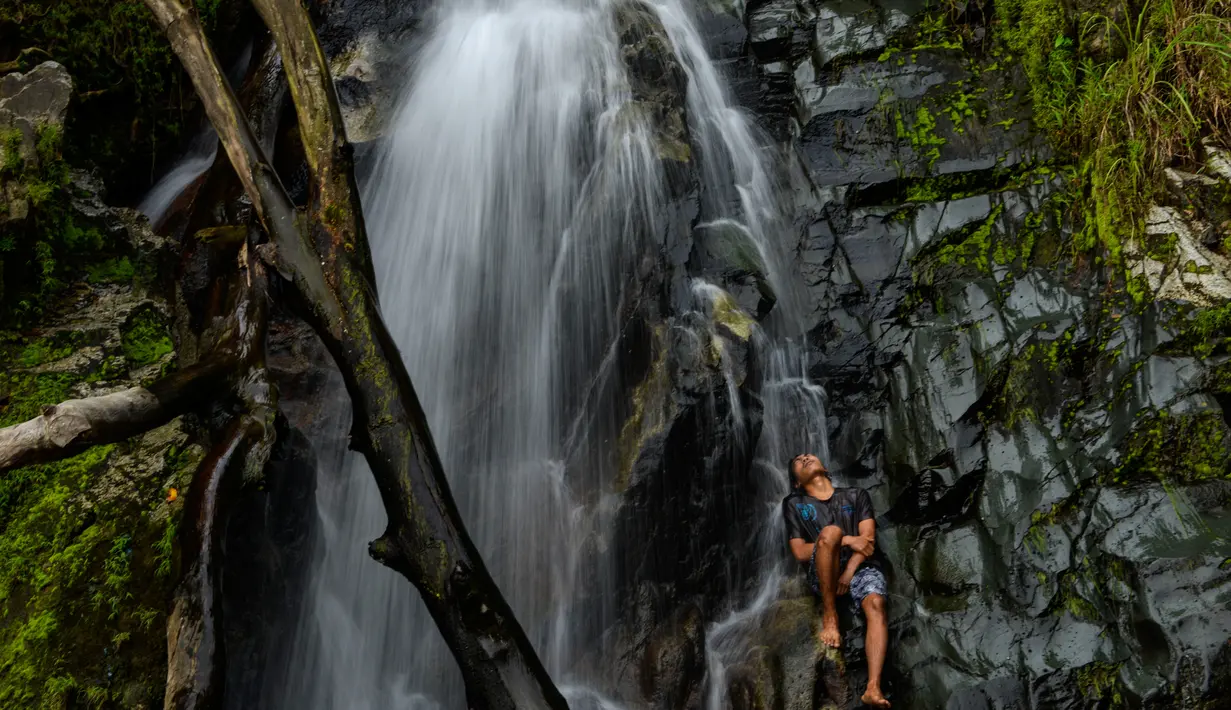 Seorang pemuda mendinginkan diri di air terjun di Samadua, Provinsi Aceh pada 9 Juli 2020. Aceh punya banyak destinasi wisata alam mempesona yang patut dikunjungi. (Photo by CHAIDEER MAHYUDDIN / AFP)