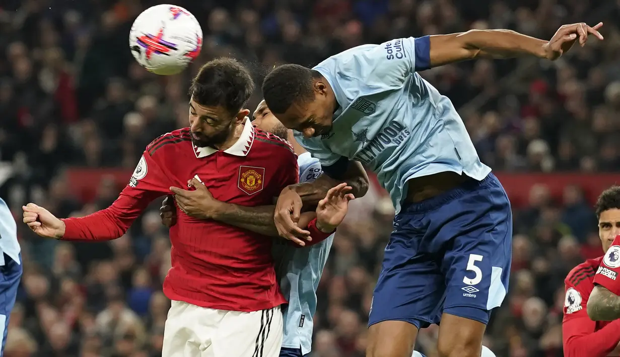 Bek Brentford, Ethan Pinnock (kanan) berduel udara dengan gelandang Manchester United, Bruno Fernandes pada laga lanjutan Liga Inggris 2022/2023 di Old Trafford Stadium, Manchester, Kamis (6/4/2023) dini hari WIB. (AP Photo/Dave Thompson)