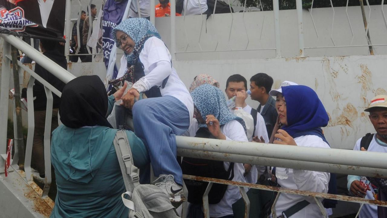 Salah satu pendukung pasangan Capres dan Cawapres nomor urut 1 Anies Baswedan-Muhaimin Iskandar (AMIN) nekat sampai memanjat pagar pintu masuk  Jakarta International Stadium (JIS), Jakarta, Sabtu (10/02/2024). Foto: merdeka.com / Arie Basuki<br>