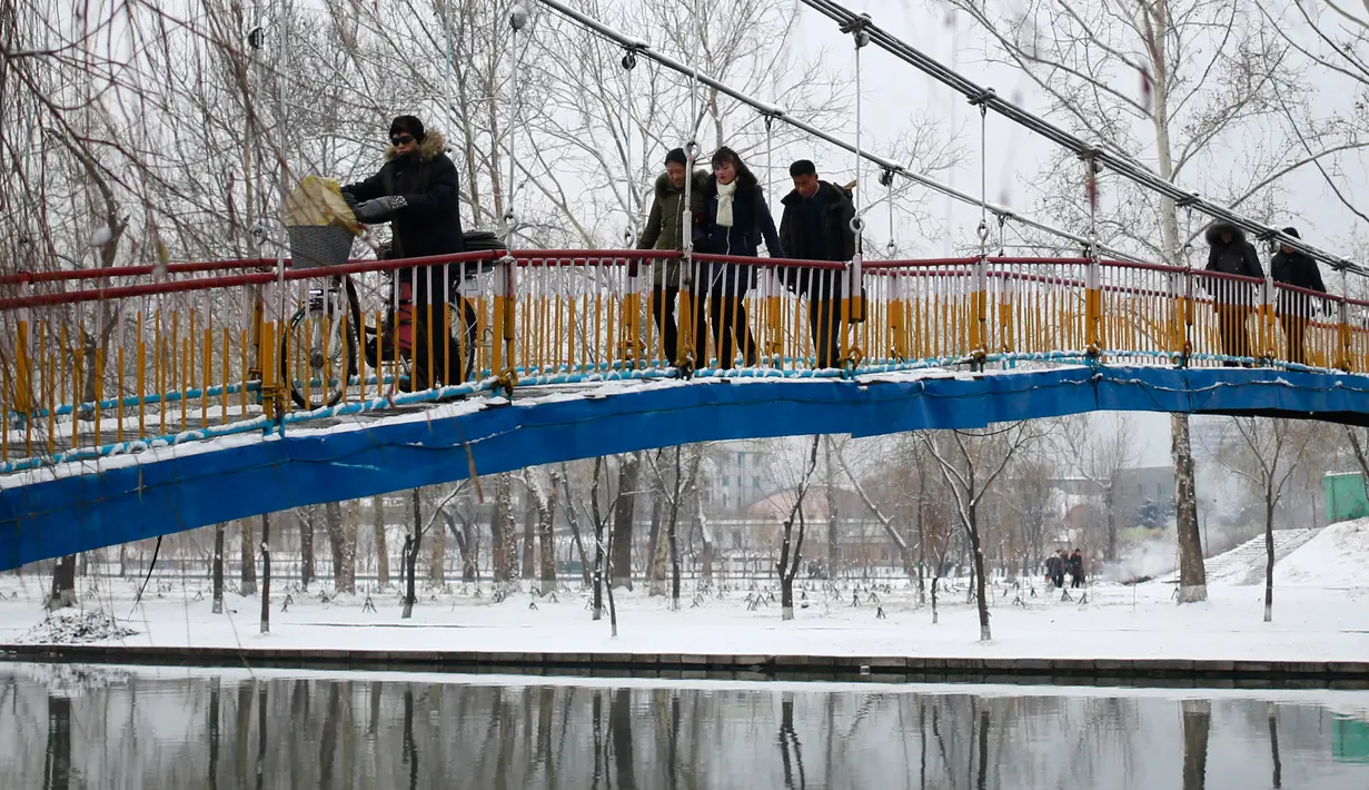 Pejalan kaki melintasi jembatan penyeberangan yang melintasi Sungai Pothong di Pyongyang, Korea Utara, Minggu (16/12). Korea Utara saat ini mulai memasuki musim dingin. (AP Photo/Dita Alangkara)