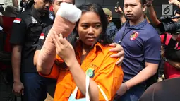 Istri tersangka pembunuhan wartawan Abdullah Fitri Setiawan alias Dufi yang tewas dalam drum, Sari menutupi wajahnya saat digelandang petugas di Polda Metro Jaya, Jakarta, Rabu (21/11). (Merdeka.com/Imam Buhori)
