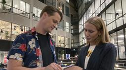 Direktur DSruptive Subdermals, Hannes Sjoblad memindai implan di tangan manajer pemasaran, Amanda Back dengan smartphone untuk mengungkapkan kartu kesehatannya di Epicenter Stockholm (20/12/2021). (AFP/Viken Kantarci)