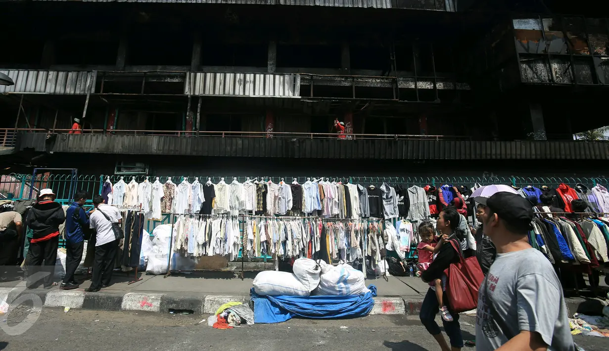  Calon pembeli melihat barang dagangan di luar pasar senen, Jakarta, Sabtu (21/1). Pasca kebakaran tidak membuat para pedangang putus asa, sebagian dri mereka ada yang tetap berjualan meskipun harua di bahu jalan. (Liputan6.com/Angga Yuniar)