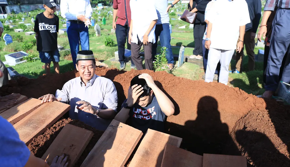 Sebagai anak, Iko juga ikut turun ke liang lahat demi membantu jenazah ayahnya untuk dimakamkan. Aktor 34 tahun itu juga mengumandangkan azan sebelum akhirnya diurug dengan tanah. (Adrian Putra/Bintang.com)