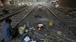 Ratan Samanta (29) tengah memasak diantara rel kereta api di Kolkata, India, 13 Maret 2016. Beberapa orang di Kolkata bekerja sebagai penjual pakaian bekas atau pengemudi becak dan mereka terlalu miskin untuk membeli rumah. (REUTERS/Rupak De Chowdhuri)