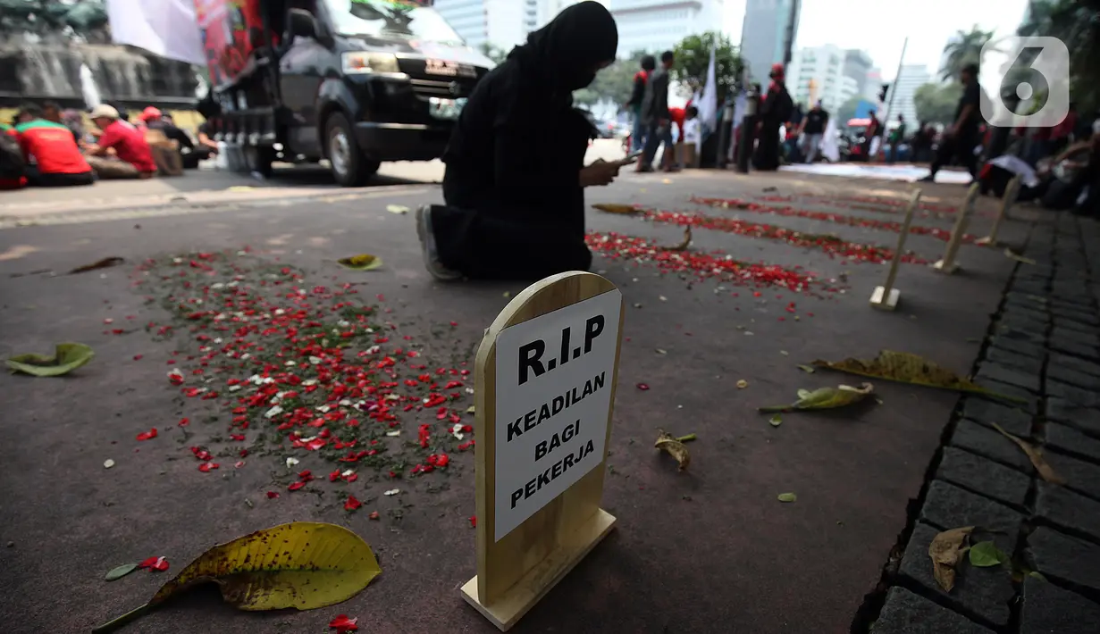 Kuburan tiruan dibuat saat karyawan IndosatM2 melakukan demonstrasi di depan Gedung PT Indosat, Jalan Merdeka Barat, Jakarta Pusat, Rabu (22/12/2021). Demonstran meminta karyawan yang telah di-PHK untuk diperkerjakan kembali serta menuntut Indosat memenuhi hak-hak karyawan. (Liputan6.cm/Johan Tallo)