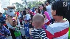 Seorang anak berfoto dengan boneka Pramuka dalam aksi Satu Indonesia di area Car Free Day (CFD), Bundaran HI, Minggu (30/7). Aksi tersebut bertajuk “Satu Nusa, Satu Bangsa, Satu Bahasa, Indonesia”. (Liputan6.com/Helmi Afandi)