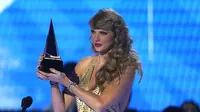 Taylor Swift menerima penghargaan untuk album pop favorit untuk "Red (Taylor's Version)" di American Music Awards di Microsoft Theater di Los Angeles pada Minggu, 20 November 2022. Taylor Swift tampil Ia mengenakan pakaian panjang berwarna gold dengan rambutnya yang panjang bergelombang. (AP Photo/Chris Pizzello)