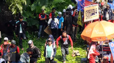 Massa buruh melintasi taman pembatas jalan di sekitar Kawasan Patung Patung Arjuna Wiwaha saat aksi perayaan hari Buruh Internasional 2017 di Jakarta, Senin (5/1). Ribuan massa buruh ikut turun ke jalan. (Liputan6.com/Helmi Fithriansyah)