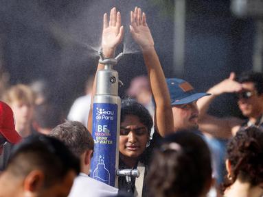 Orang-orang menyegarkan diri di sebuah taman publik selama gelombang panas di Paris, pada 30 Juni 2025. (Ludovic MARIN/AFP)