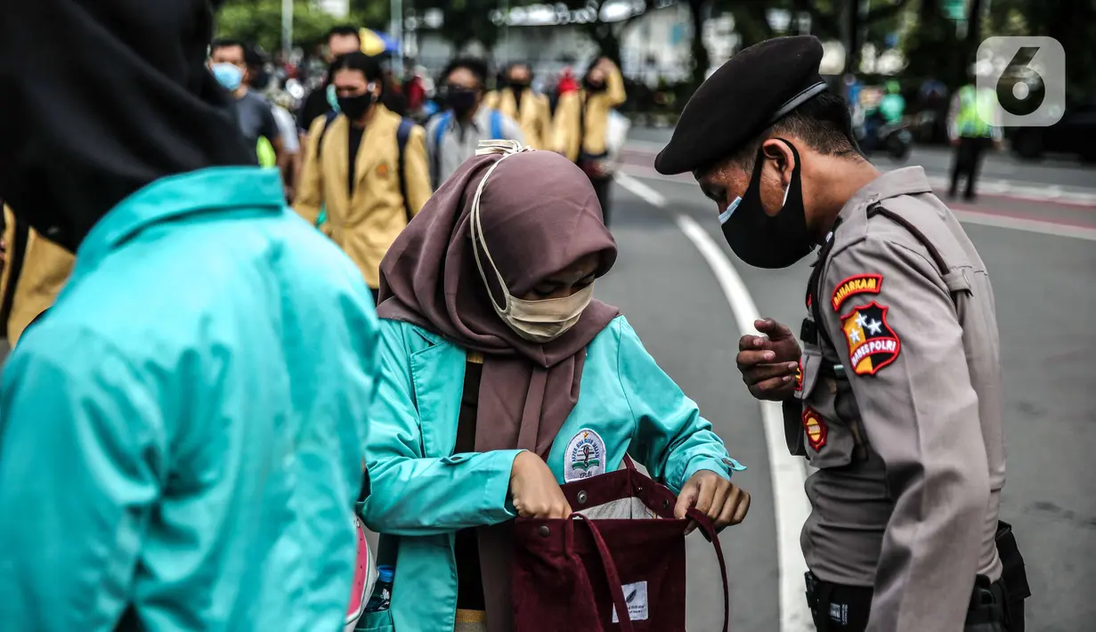 Polisi memeriksa barang bawaan mahasiswa yang akan berunjuk rasa di Patung Kuda, Jakarta, Selasa (20/10/2020). Pemeriksaan tersebut dilakukan untuk memastikan unjuk rasa berjalan aman dan damai. (Liputan6.com/Faizal Fanani)