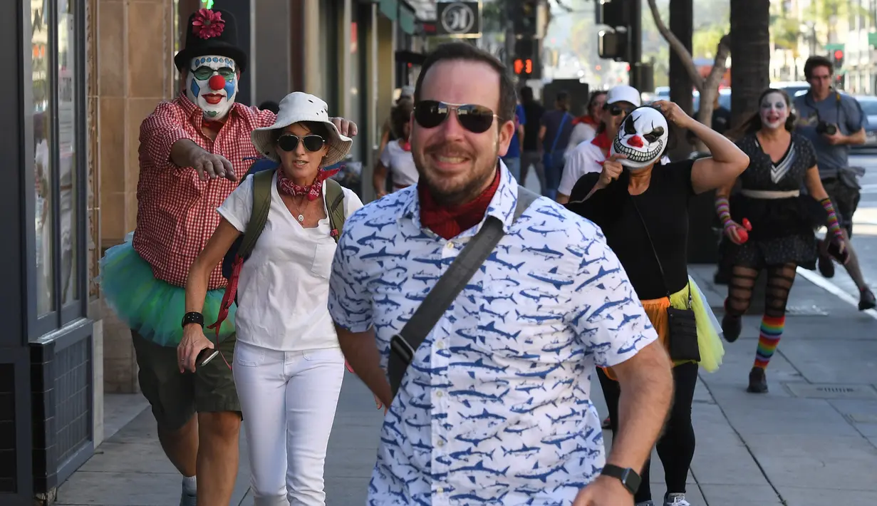 Peserta berdandan seperti badut mengejar pejalan kaki selama 'Running of the Clowns' di Pasadena, California pada 21 Oktober 2018. Lari dikejar kawanan badut ini merupakan parodi yang mengolok-olok lomba dikejar banteng di Spanyol. (Mark RALSTON/AFP)