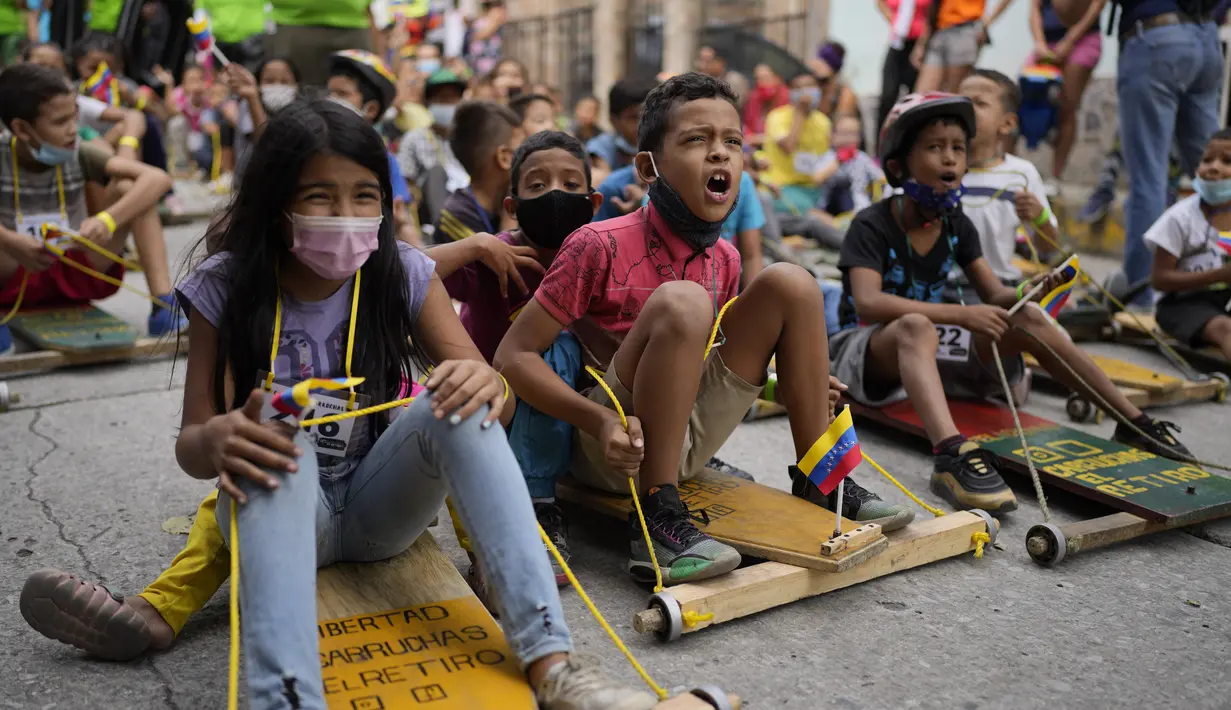 Anak-anak berpartisipasi dalam perlombaan jalanan tradisional "carruchas", sebutan untuk mobil kayu darurat di Caracas, Venezuela, Sabtu (18/12/2021). Anak-anak menikmati perlombaan yang menandai 10 tahun melestarikan tradisi ini. (AP Photo/Ariana Cubillos)