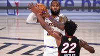 Pebasket Los Angeles Lakers, LeBron James, berusaha melewati pebasket Miami Heat, Jimmy Butler, pada laga Gim ketiga Final NBA, Senin (5/10/2020). Miami Heat menang dengan skor 115-104. (AP Photo/Mark J. Terrill)