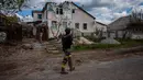 Seorang tentara dari unit pasukan khusus Ukraina Kraken berjalan melewati sebuah rumah yang hancur di desa Rus'ka Lozova pada 16 Mei 2022. Ukraina mengatakan pasukannya telah menguasai kembali wilayah di Perbatasan Rusia dekat kota terbesar kedua di negara itu Kharkiv, yang terus-menerus diserang sejak invasi Moskow dimulai. (Dimitar DILKOFF / AFP)