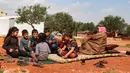 Abderrazaq Khatoun, beristirahat dengan 11 cucunya yang yatim piatu di luar tenda di desa Harbanoush, di Idlib, Suriah pada 11 Maret 2021. Perang Suriah yang merampas 13 anak Khatoun dan salah satu istrinya, membuat kakek 83 tahun itu membesarkan 11 cucu yatim piatu sendirian. (Ahmad al-ATRASH/AFP)
