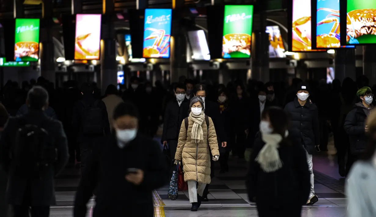 <p>Orang-orang yang memakai masker berjalan di stasiun Shinagawa di Tokyo (18/1/2022). Jepang melaporkan rekor tertinggi infeksi Covid-19 baru yang dipicu oleh varian Omicron. (AFP/Philip Fong)</p>