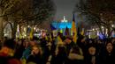 Para pengunjuk rasa tiba di Gerbang Brandenburg, diterangi dengan warna bendera Ukraina, saat demonstrasi untuk menandai peringatan satu tahun invasi besar-besaran Rusia ke Ukraina di Berlin, Jerman, 24 Februari 2023. (AP Photo/Markus Schreiber)
