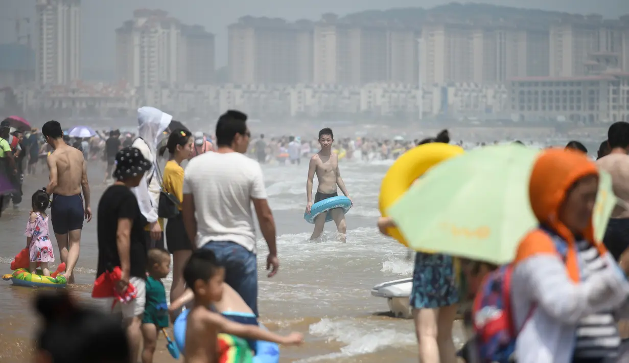 Orang-orang mengunjungi pantai sambil mendinginkan diri di Qingdao, China timur, pada 3 Agustus 2019. Banyak warga di Negeri Tirai Bambu memanfaatkan musim panas dengan mengunjungi pantai untuk mengisi liburan. (Photo by FRED DUFOUR / AFP)