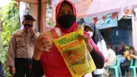 Warga menunjukkan minyak goreng dan daging kerbau seusai mengikuti vaksinasi covid-19 di kawasan Tanah Tinggi, Kota Tangerang, Jumat (4/3/2022). Pemkot Tangerang mengadakan operasi pasar minyak dan daging murah bagi warga yang melaksanakan vaksin covid-19 di lokasi. (Liputan6.com/Angga Yuniar)