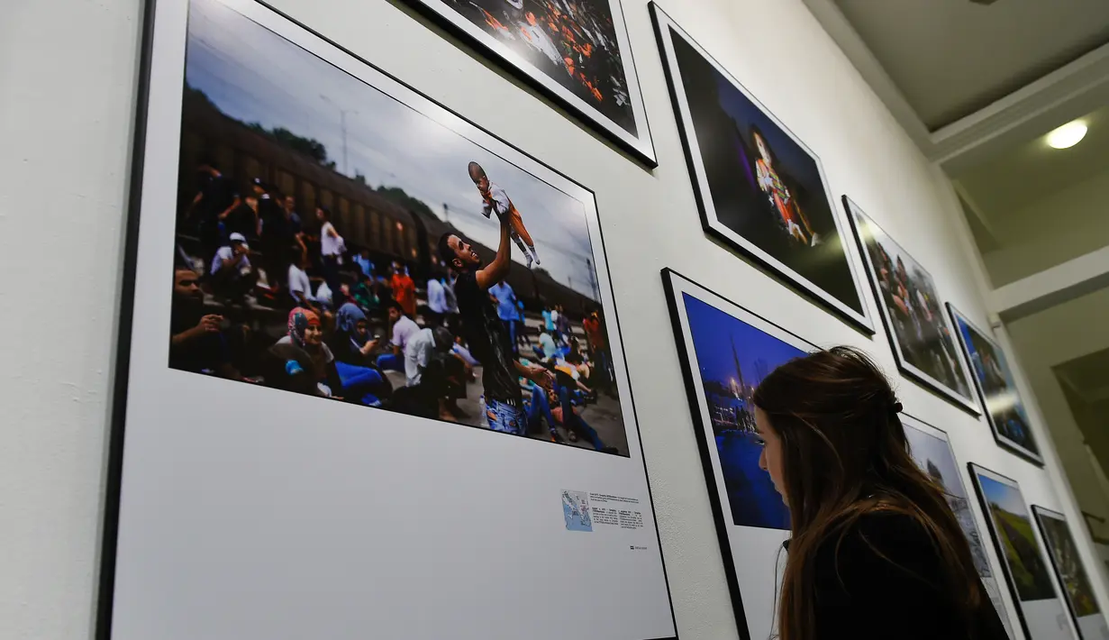 Pengunjung melihat foto karya fotografer Agence France-Presse (AFP) mengenai krisis migrasi di Eropa di pusat seni Bozar di Brussels (3/5). Pameran ini menampilkan foto-foto imigran dari Suriah, Irak sampai Turki dan Laut Tengah. (AFP Photo/John Thys)
