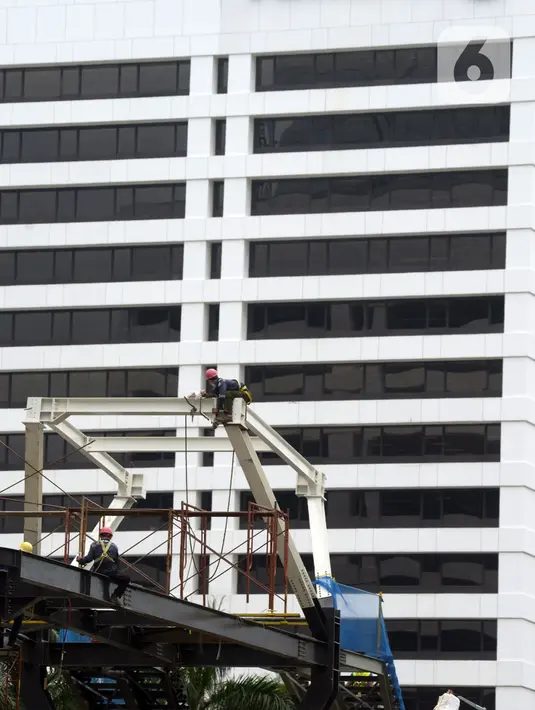 Pekerja menyelesaikan proyek Tugu Tenaga Kesehatan di Jembatan Penyeberangan Orang (JPO) Sudirman, Jakarta, Jumat (12/11/2021). Pemprov DKI Jakarta membuat Tugu Tenaga Kesehatan untuk menghormati tenaga kesehatan yang gugur selama pandemi COVID-19. (merdeka.com/Imam Buhori)