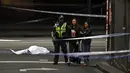 Polisi membawa warga menjauh dari TKP setelah insiden penikaman di Melbourne, Australia, Jumat (9/11). Pelaku menabrakkan mobil dan membakarnya sebelum menusuk tiga orang sekitar. (William WEST/AFP)