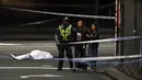 Polisi membawa warga menjauh dari TKP setelah insiden penikaman di Melbourne, Australia, Jumat (9/11). Pelaku menabrakkan mobil dan membakarnya sebelum menusuk tiga orang sekitar. (William WEST/AFP)
