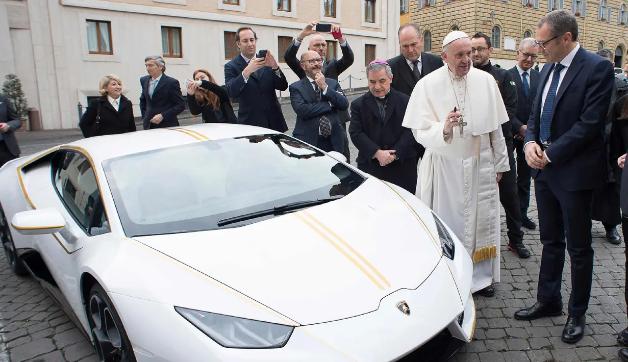 Paus Fransiskus saat menerima hadiah mobil Lamborghini Huracan di Vatikan, Rabu (15/11). Mobil Lamborghini ini oleh Paus rencananya akan dilelang dan hasilnya akan digunakan untuk membantu jemaah Kristen di Irak. (L'Osservatore Romano/Pool Photo via AP)