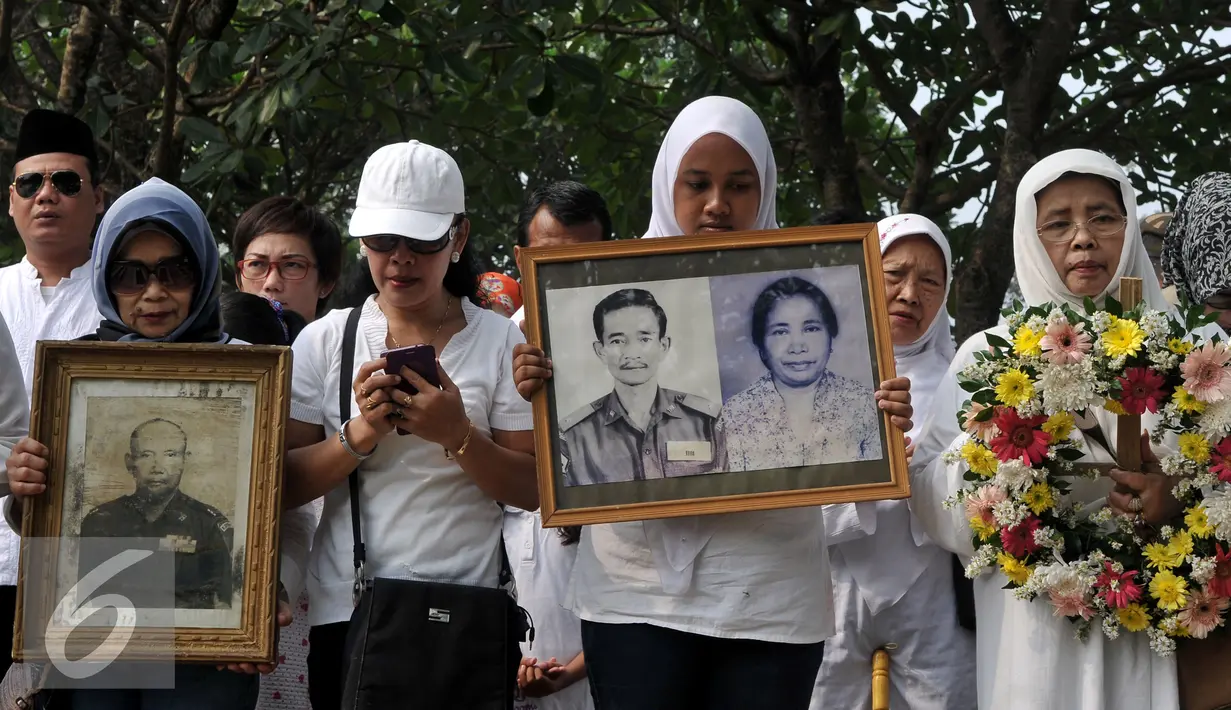 Warga Kompleks Zeni Mampang membawa foto keluarga mereka saat ziarah di TMP Kalibata, Jakarta, Minggu (1/11/2015). Mereka akan membongkar makam keluarga mereka di TMP jika pemerintah melakukan penggusuran terhadap rumah mereka. (Liputan6.com/Johan Tallo)