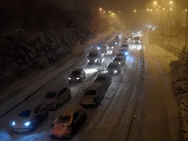 Sejumlah mobil terjebak salju tebal yang menyelimuti Jalan Lingkar M30 di Madrid, Spanyol, Jumat (8/1/2021). Ribuan mobil terjebak salju tebal akibat Badai Filomena yang menghantam Madrid dan sebagian besar wilayah Spanyol. (OSCAR DEL POZO/AFP)