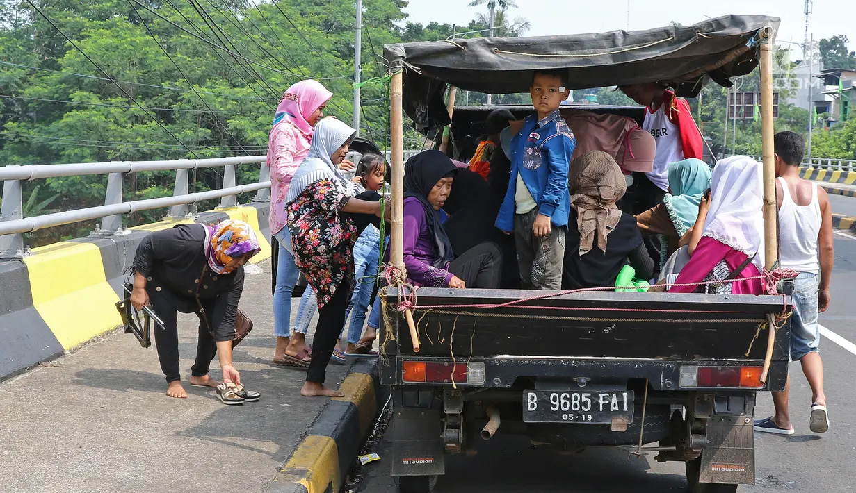 Warga menumpang kendaraan bak terbuka untuk menuju Kebun Binatang Ragunan di kawasan Jakarta, Minggu (9/6/2019). Masyarakat memanfaatkan truk dan mobil bak terbuka untuk bepergian saat libur lebaran karena dianggap lebih hemat biaya. (Liputan6.com/Herman Zakharia)
