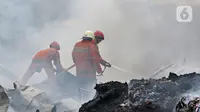 Petugas pemadam kebakaran melakukan pendingin di Pabrik penggilingan kapas,  Pasar Rebo, Jakarta Timur, Selasa (16/11/2021). Api melalap Pabrik penggilingan kapas yang di sebabkan korsleting pada panel listrik. (Liputan6.com/Herman Zakharia)