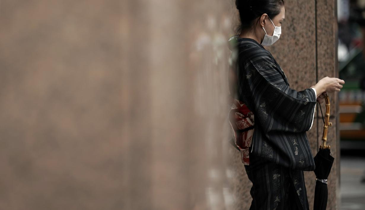 Seorang wanita berkimono tradisional Jepang yang mengenakan masker untuk membantu mencegah penyebaran virus corona berjalan di Tokyo, Kamis (10/9/2020). Ibu kota Jepang itu mengonfirmasi lebih dari 270 kasus virus corona pada Kamis. (AP Photo / Eugene Hoshiko)