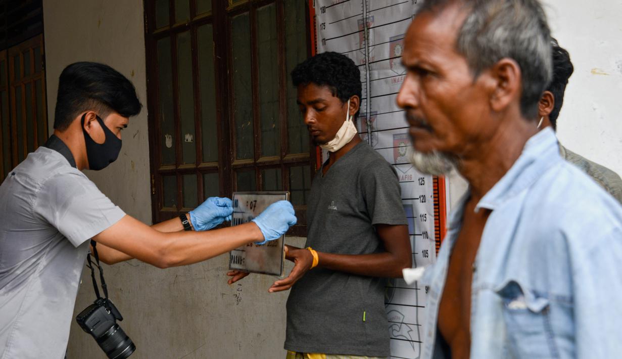 Seorang pria Rohingya (tengah) saat menjalani prosedur identifikasi oleh kepolisian Aceh di pusat penampungan sementara bekas kantor Imigrasi Punteuet di Lhokseumawe, Aceh Utara (26/6/2020). (AFP Photo/CHAIDEER MAHYUDDIN)