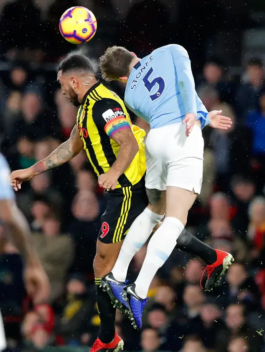 Pemain Watford, Troy Deeney berebut bola udara dengan bek Manchester City, John Stones selama pertandingan lanjutan Liga Inggris di stadion Vicarage Road (4/12). City menang tipis atas Watford 2-1. (AP Photo/Frank Augstein)