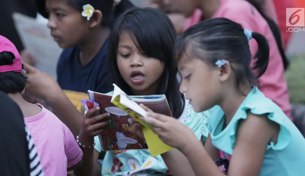 Sejumlah anak membaca buku di mobil Perpustakaan Keliling Dinas Perpustakaan dan Arsip Daerah Kabupaten Klungkung di lokasi pengungsian korban evakuasi Gunung Agung, Klungkung, Bali, Sabtu (30/09). (Liputan6.com/Gempur M Surya)