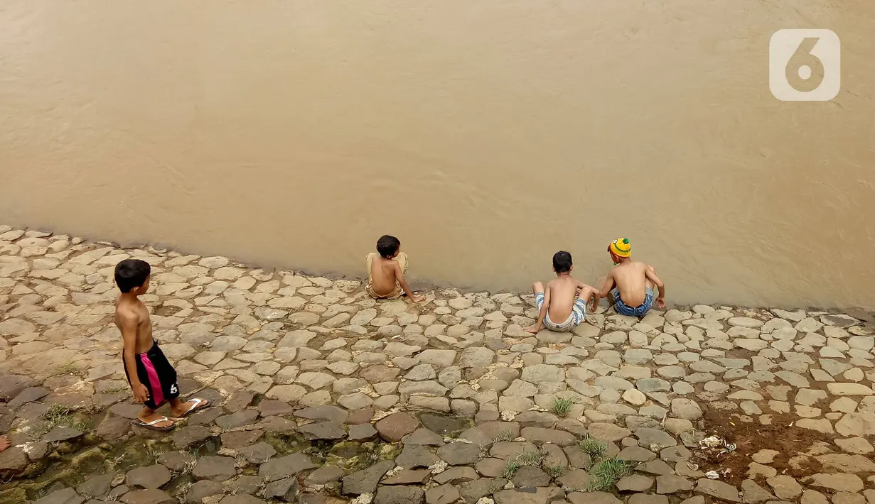 Sejumlah anak bermain di Bantaran sungai Kanal Banjir Barat, Tanah Abang, Jakarta, Sabtu (4/1/2020). Minimnya lahan bermain terpaksa membuat anak-anak harus bermain di bantaran Banjir Kanal Barat meskipun dapat membahayakan keselamatan dirinya. (Liputan6.com/Angga Yuniar)