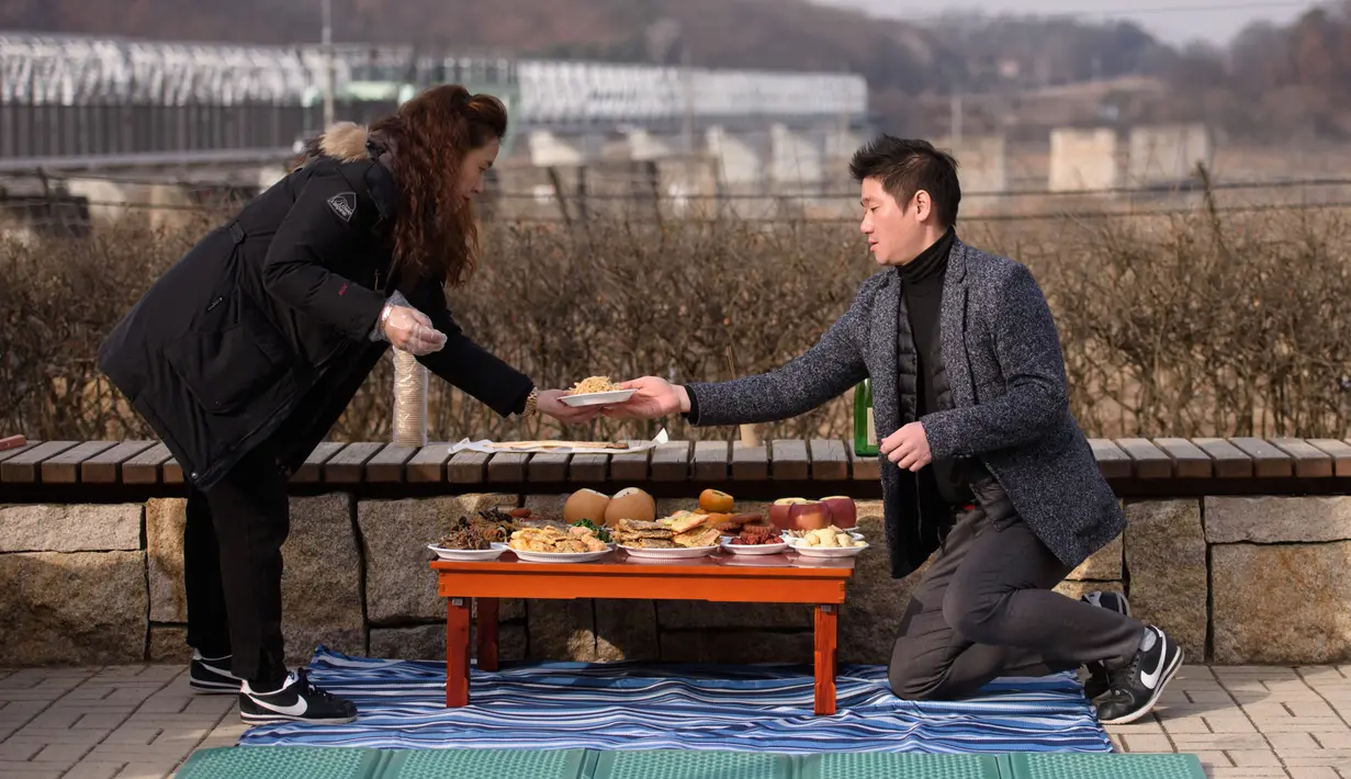 Pengungsi Korea Utara, Kim Jung-ae (kiri) mengatur meja untuk memberikan penghormatan kepada kerabat dan leluhur pada Tahun Baru Imlek di “desa harapan” Imjingak, dekat zona demiliterisasi yang memisahkan kedua Korea di Paju, Selasa (5/2). (Ed JONES/AFP)