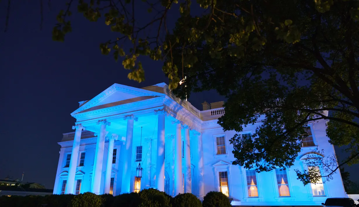 Gedung Putih menyala dengan warna biru untuk menandai World Autism Awareness Day atau Hari Peduli Autisme Sedunia di Washington, Kamis (2/4/2020). Hari Peduli Autisme Sedunia jatuh setiap 2 April semenjak ditetapkan melalui sebuah resolusi PBB di tahun 2007. (MANDEL NGAN / AFP)