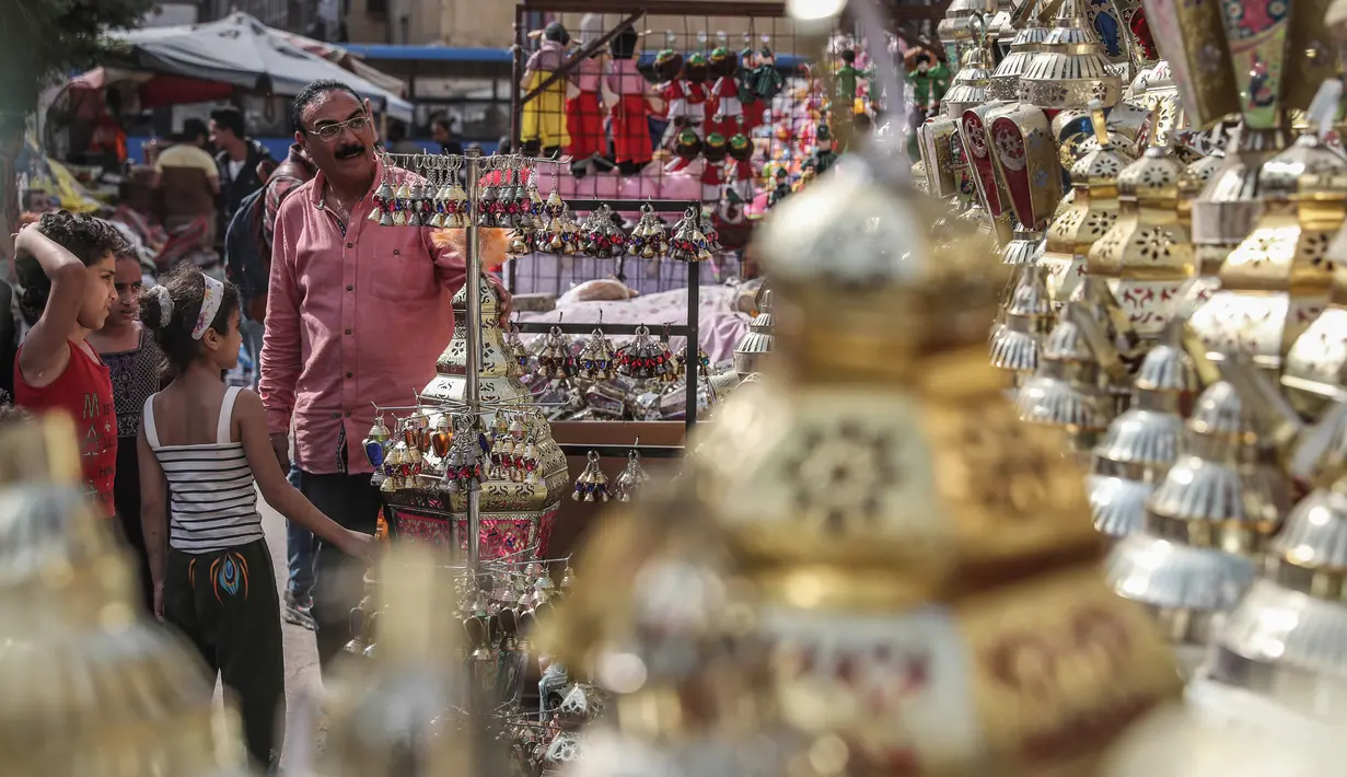 Keluarga Mesir melihat lentera tradisional yang dikenal dalam bahasa Arab sebagai "Fanous" yang dijual selama bulan suci Ramadan di Sayeda Zainab, Kairo, 17 April 2020.  Menjelang Ramadan 1441 H, warga Mesir mulai berburu lentera warna-warni di tengah pandemi corona Covid-19. (Mohamed el-Shahed/AFP)