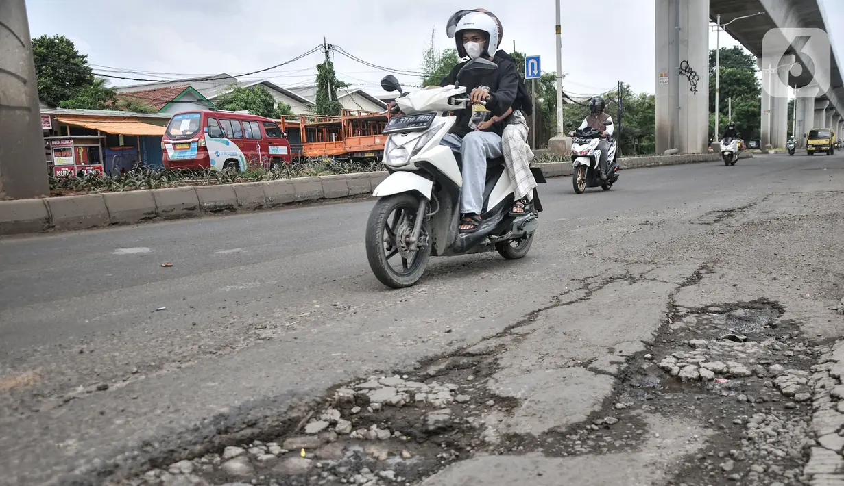 Pengendara motor melintasi Jalan Raya Bekasi,  yang rusak dan berlubang di Cakung, Jakarta Timur, Selasa (14/3/2023). Minimnya perawatan menyebabkan kondisi Jalan Raya Bekasi arah Cakung ke Pulogebang rusak dan berlubang yang dapat membahayakan keselamatan pengendara, terlebih saat musim penghujan. (merdeka.com/Iqbal S Nugroho)