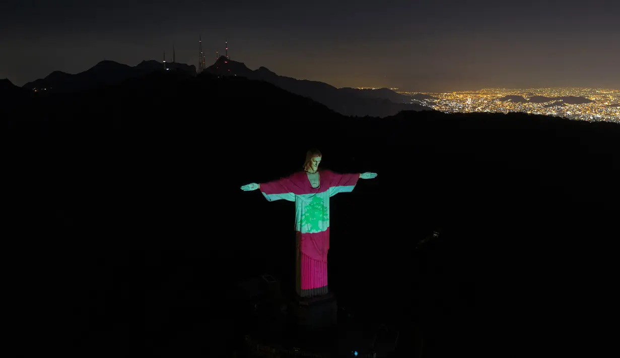Patung Christ the Redeemer menyala dengan gambar bendera nasional Lebanon di Rio de Janeiro, Brasil, Kamis (6/8/2020). Tindakan tersebut sebagai bentuk solidaritas bagi para korban ledakan dahsyat yang mengguncang ibu kota Lebanon, Beirut pada Selasa (4/8) lalu. (AP Photo/Leo Correa)