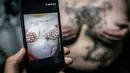 Yevgeniya Zakhar menunjukkan foto tubuh Lilya, seorang korban KDRT sebelum ditutupi dengan tato yang ia buat, di Ufa, Rusia, (4/12/2016). Bekas luka para korban KDRT ditato bergambar motif floral oleh Yevgeniya Zakhar. (AP Photo/Vadim Braydov)