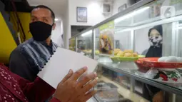 Pengunjung tuna netra memilih menu makanan menggunakan panduan buku braille di Warteg FAST, Graha Raya Bintaro, Tangerang Selatan, Banten, Kamis (3/12/2020). Hari ini diperingati Hari Penyandang Disabilitas Internasional. (merdeka.com/Dwi Narwoko)