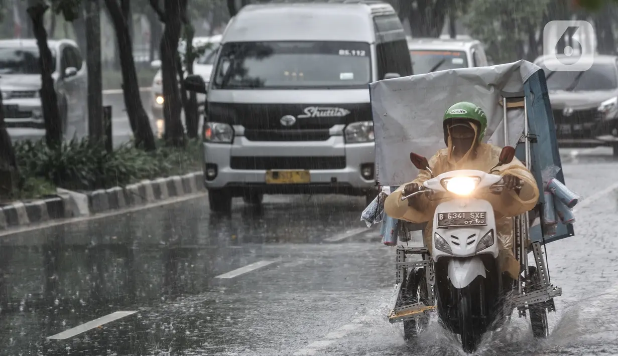 Pengendara menerobos hujan di Jalan Pramuka, Jakarta, Kamis (18/2/2021). Badan Meteorologi Klimatologi dan Geofisika (BMKG) mengimbau pengguna jalan agar berhati-hati saat berkendara karena hujan disertai angin kencang diprediksi terus berlanjut hingga akhir Februari. (merdeka.com/Iqbal S Nugroho)